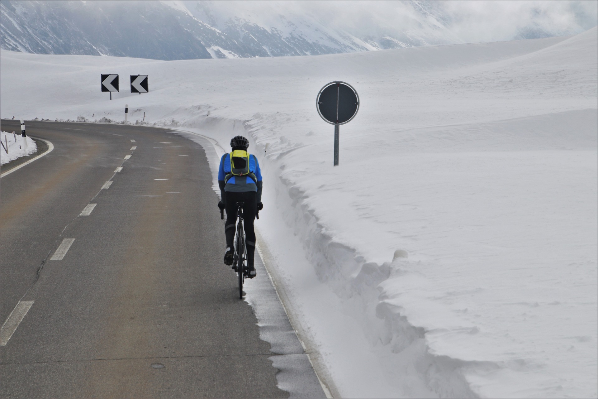 Rennradfahrer von Hinten, der durch eine schneebedeckte Landschaft fährt